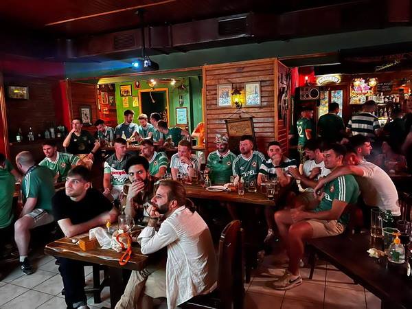 Fans in green jerseys watching the match
